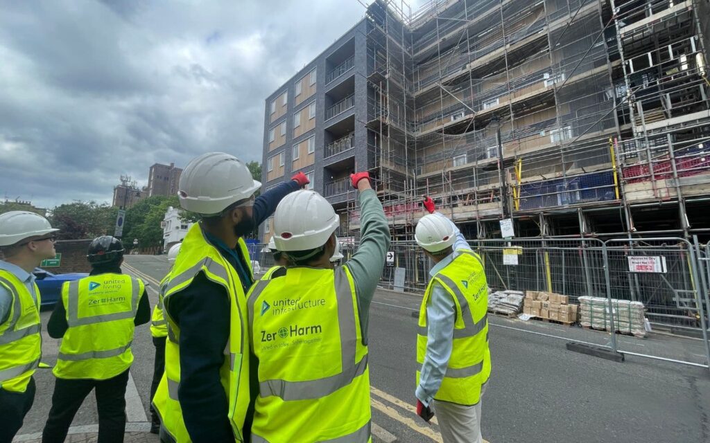 students wearing ppe standing in front of apartment building with scaffolding