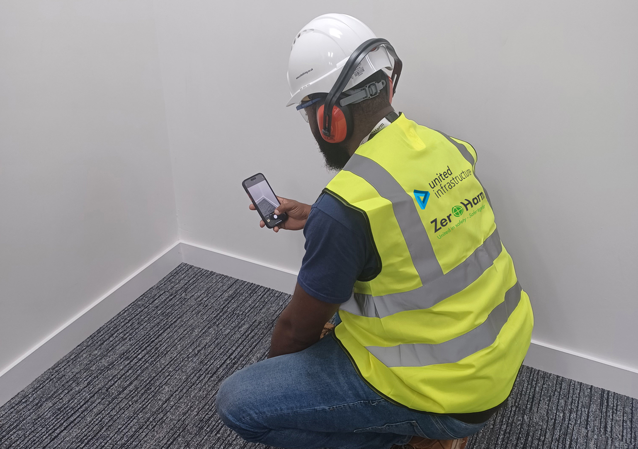 employee taking photo of internal wall with phone