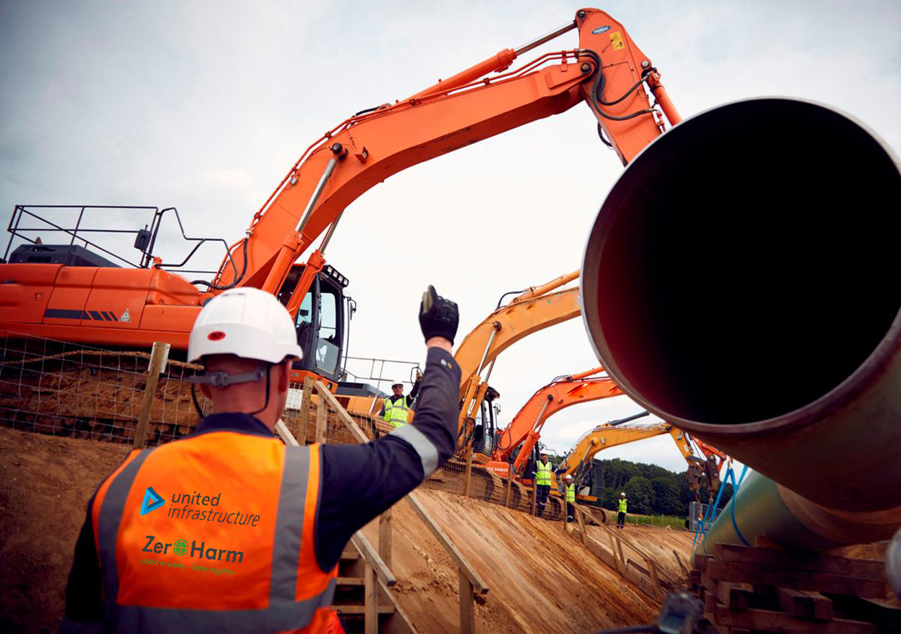 cranes lowering gas pipes into ground