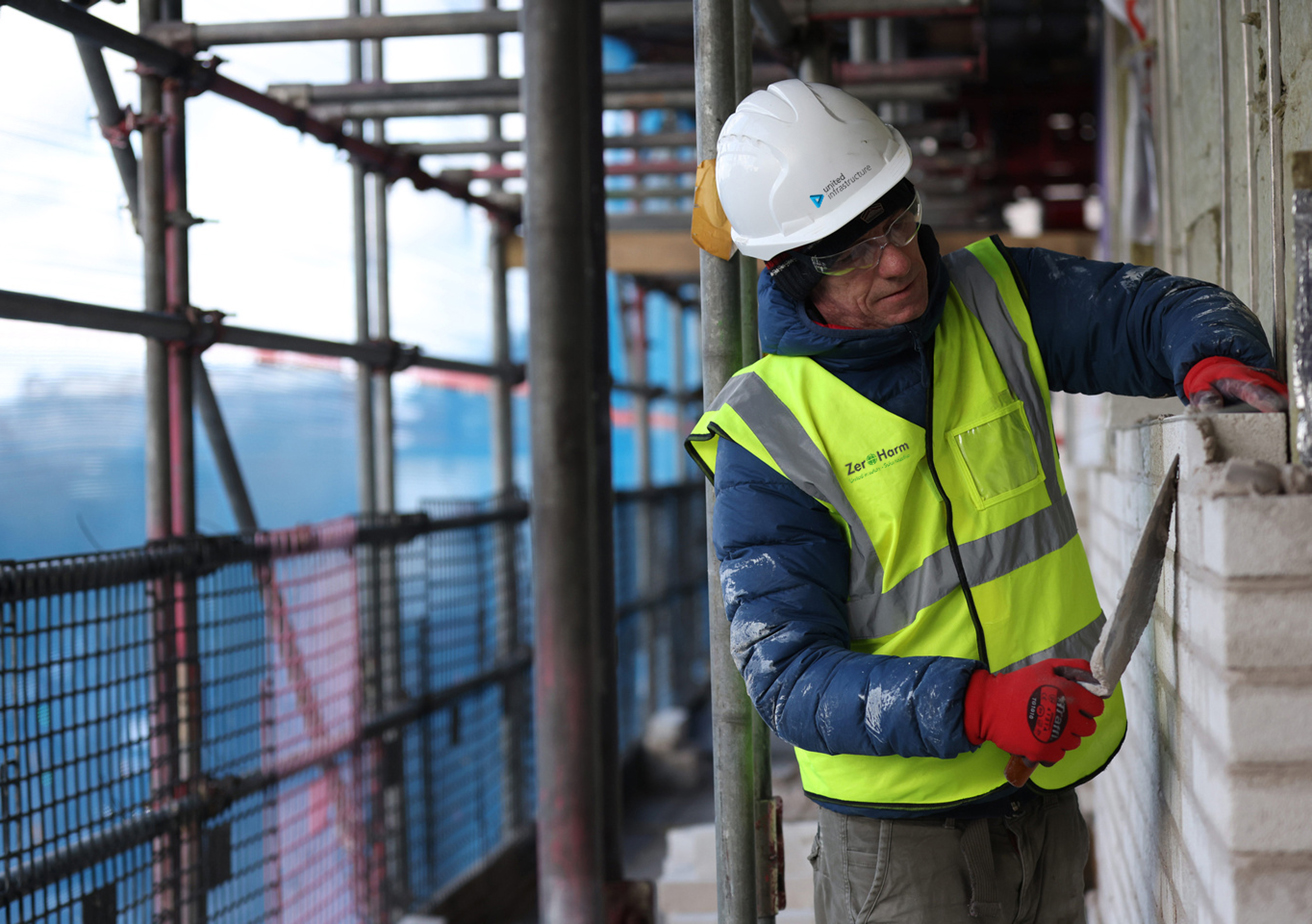 united infrastructure employee working on site next to scaffolding