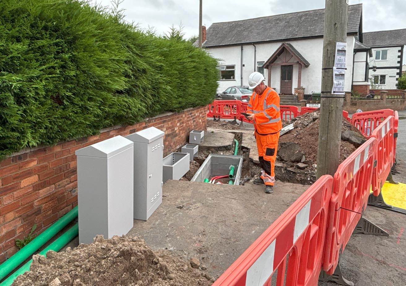 employee working on excavated ground on residential street with safety barriers
