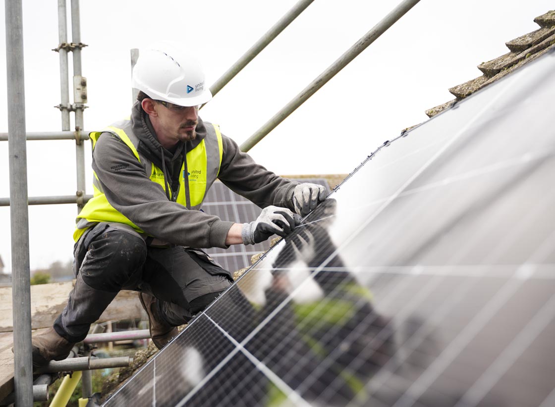 united infrastructure employee fitting solar panels on roof