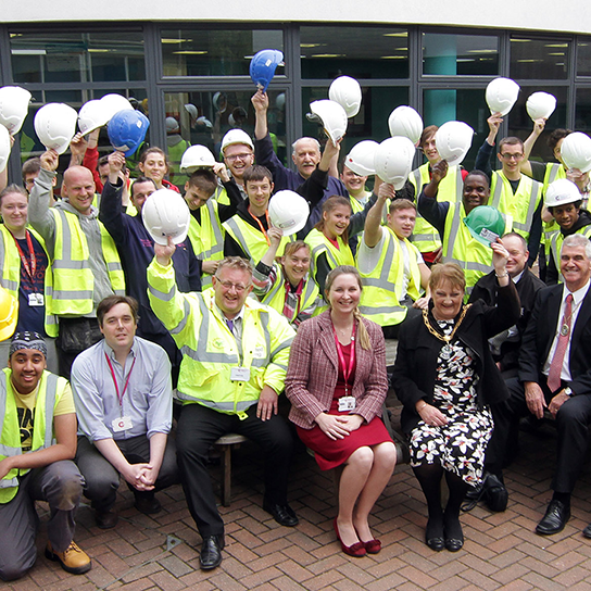 our people united living employee group photo holding up hard hats