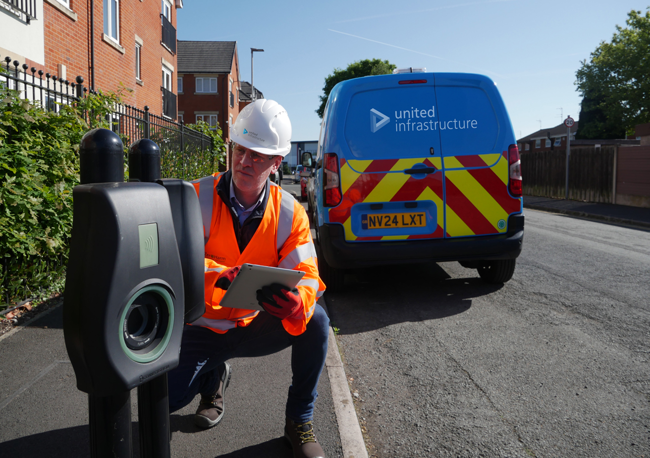 engineer inspecting ev chargin point with united living van in background