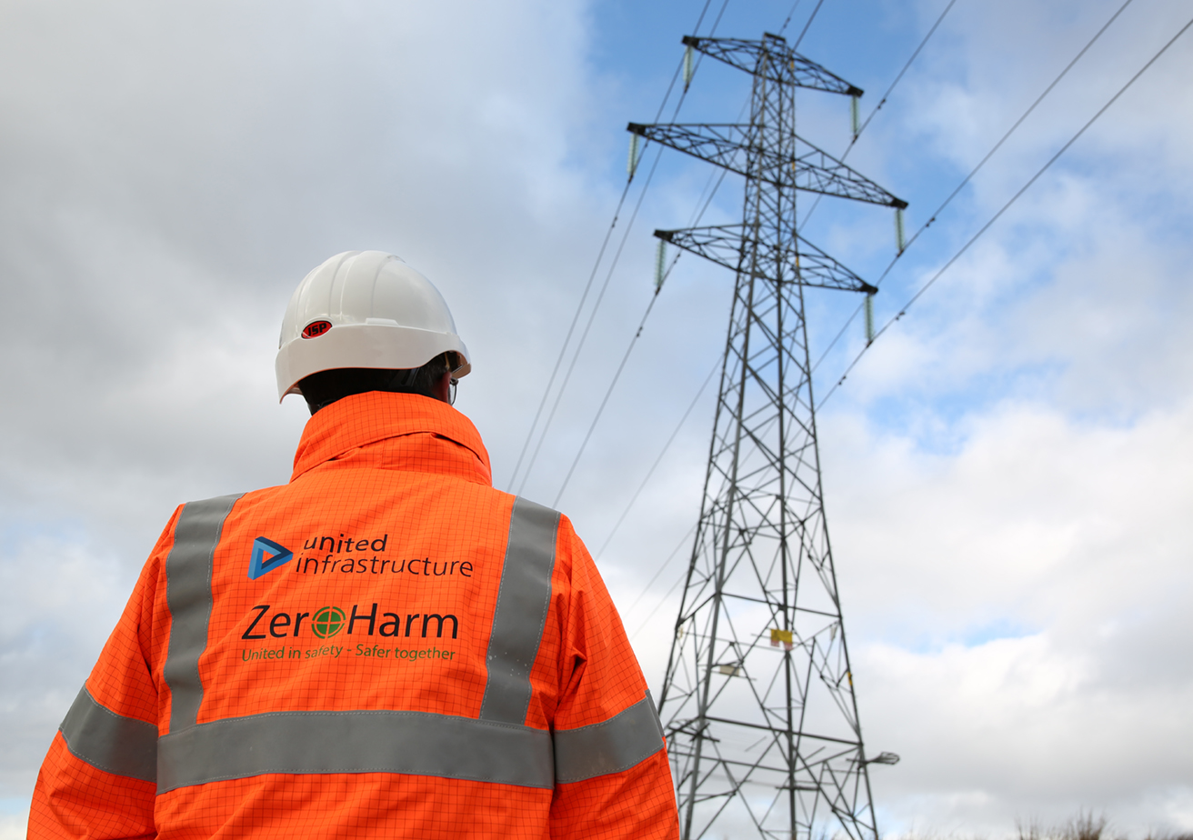 power infrastructure employee standing in front of pylon