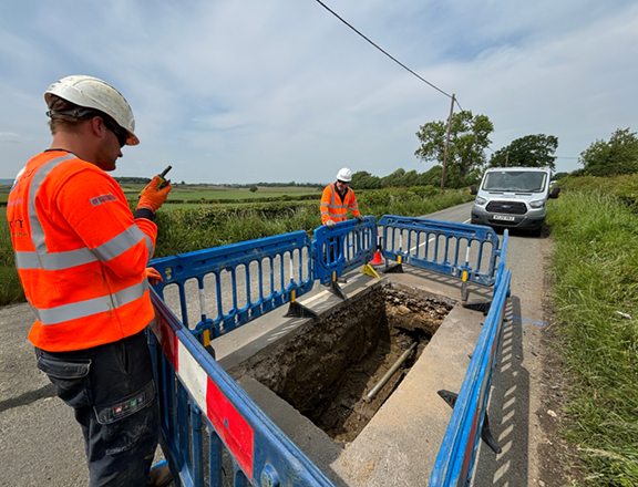 construction worker standing over excavated ground surrounded by safety barriers