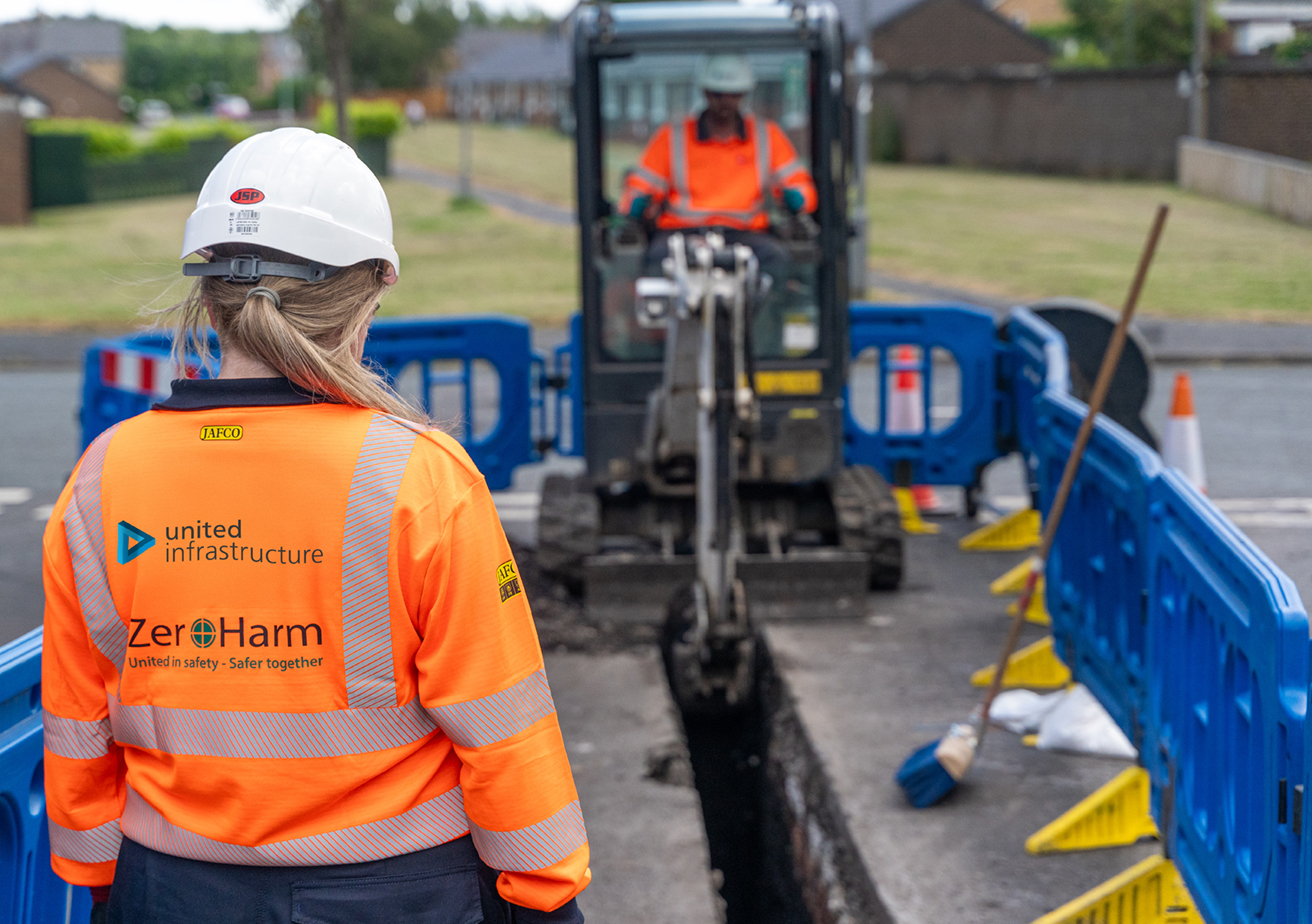 construction worker overseeing digger completing excavation works