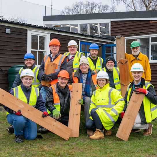 group of employees outside hold pieces of wood