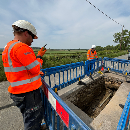 construction worker standing over excavated ground surrounded by safety barriers