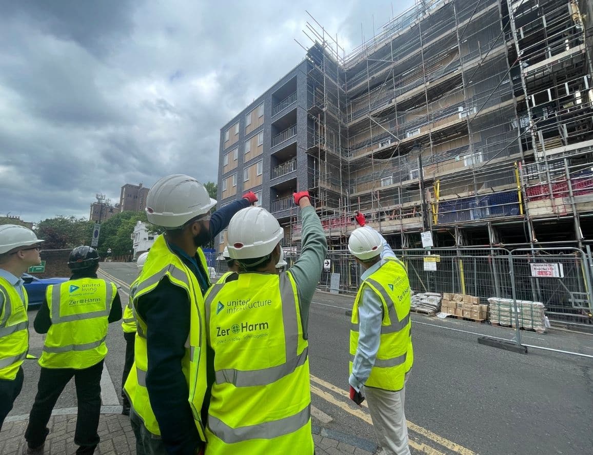 students wearing ppe standing in front of apartment building with scaffolding