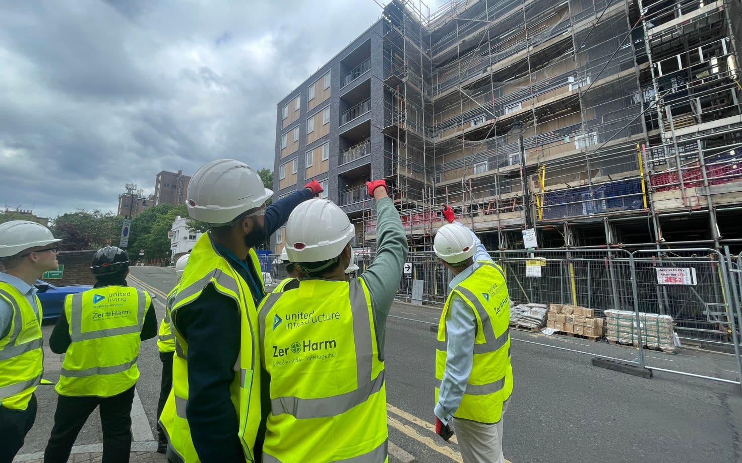 students wearing ppe standing in front of apartment building with scaffolding