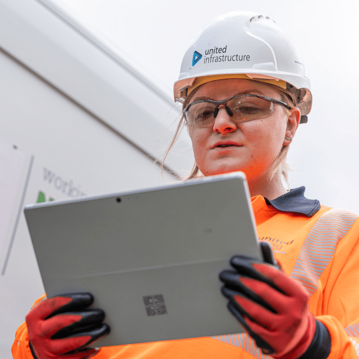 Employee standing in front of van in pee and holding an electronic tablet